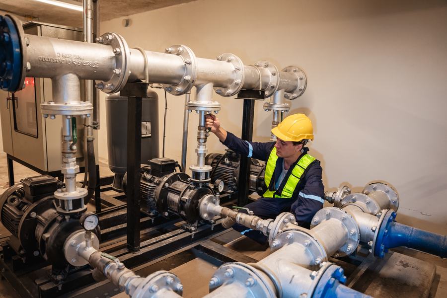 Técnico ajustando válvulas en un cuarto de bombas